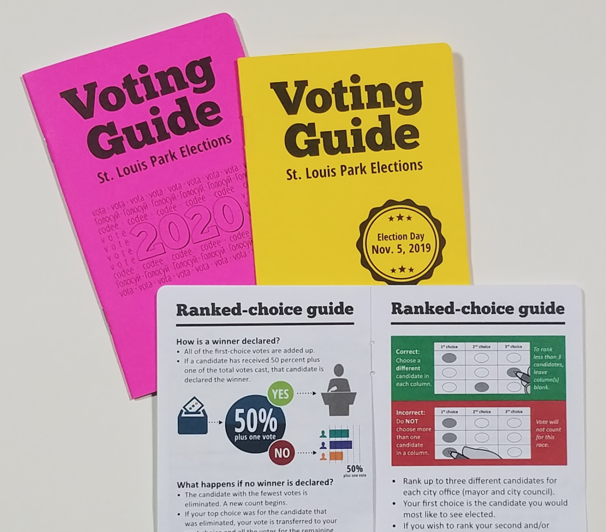 Two guides with bright colored pink and yellow covers. Open page showing ranked choice voting information