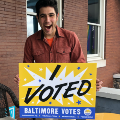 Sam Novey holding an I Voted - Baltimore Votes sign
